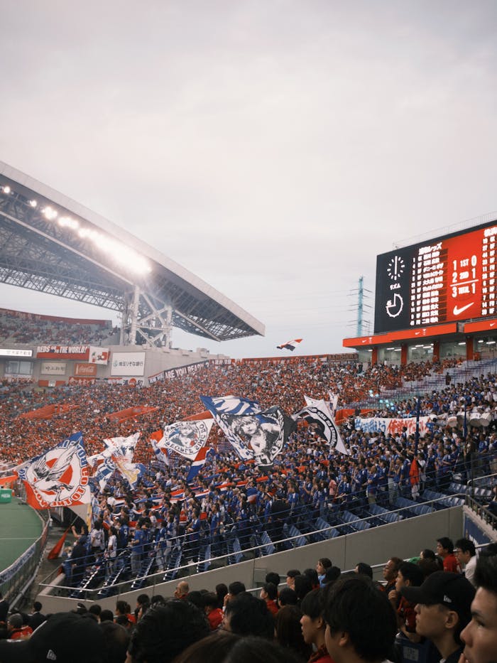 Colorful soccer fans cheering in a vibrant stadium atmosphere, waving flags and banners.